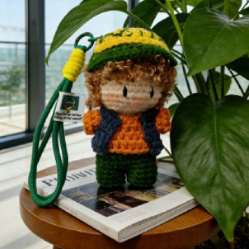 Handmade crochet girl keychain photographed in a garden-inspired setting